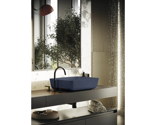 Modernt badrum med blått tvättställ, svart armatur och stilren inredning