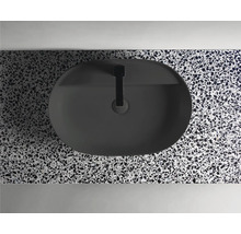 Ovanifrån en oval, svart tvättställsskål med armatur på en bänkskiva med terrazzomönster.