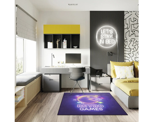 Modernt ungdomsrum med skrivbord, säng och blå matta med retrospelsmotiv.