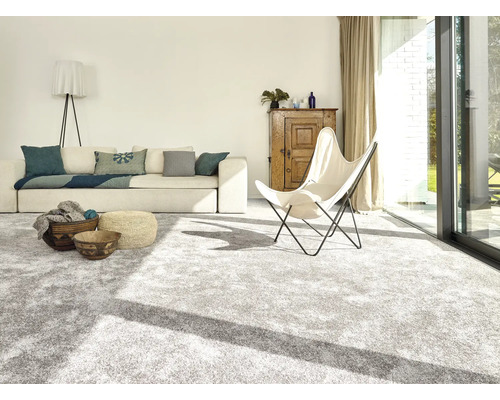 Ljust vardagsrum med heltäckningsmatta, soffa, fåtölj och träelement för en vänlig atmosfär