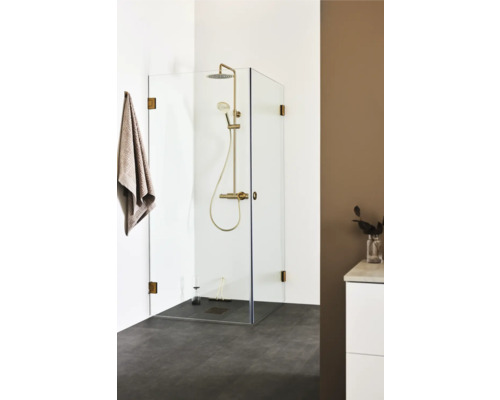 Duschkabin med gyllene duschblandare och handduk