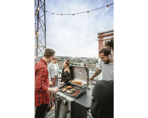 Grupp av människor grillar utomhus på en gasolgrill