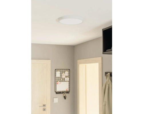 Taklampa i ett rum med en dörr, en anslagstavla och en klädhängare