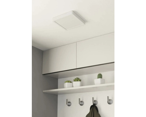 Fyrkantig taklampa i ett rum med hyllor och en hängare.