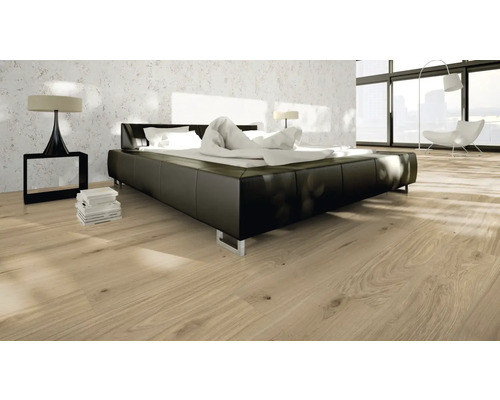 Sovrum med en säng, ett sängbord, en lampa och ett trägolv.