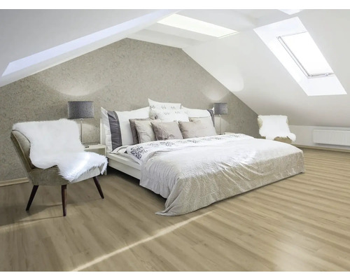 Ljust vindsrum med säng, stolar och takfönster.