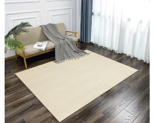 Ett vardagsrum med en ljusfärgad matta i fiskbensmönster, en soffa, gardiner och en krukväxt