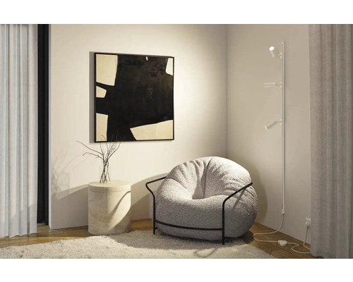 Vardagsrum med fåtölj, golvlampa och abstrakt konst