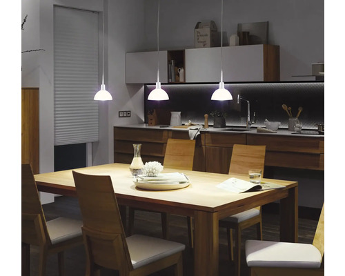 Matsal med matbord, stolar och pendellampor.