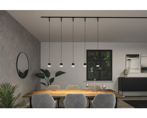 Matsal med matbord, stolar och svart strömskena med hängande armaturer