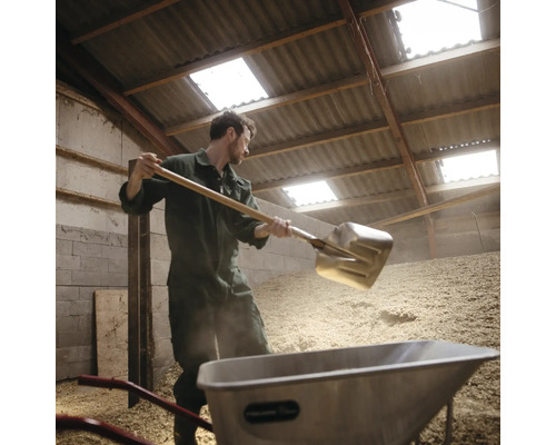 Man med spade och skottkärra i ett lager