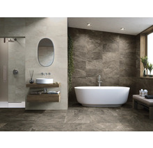 Badrum med dusch, handfat, spegel och fristående badkar mot en kakelvägg.