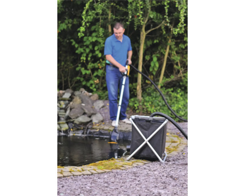 Man använder en dammsugare för damm för att rengöra en trädgårdsdamm.