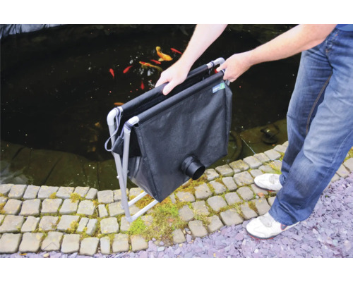 Person håller en dammsugare över en trädgårdsdamm