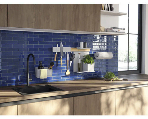 Köksscen med diskho, kran, arbetsbänk och diverse köksredskap på ett väggfäste