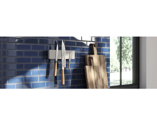 Köksscen med blått kakel, magnetisk knivhållare med knivar och skärbrädor i trä