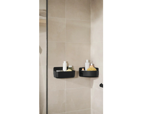 Två svarta duschkorgar med badrumsartiklar på en badrumsvägg