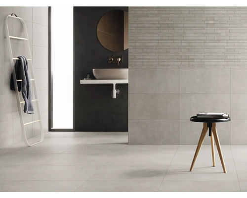 Ljust badrum med kakel, handfat och stegställning för handdukar