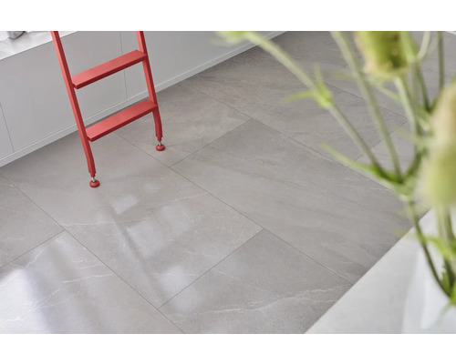 Ljust rum med golvplattor i stenlook och röd stege