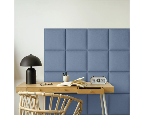 Miljöbild med skrivbord, lampa, bok, glasögon, pennor, klocka, stol och vadderade väggpaneler