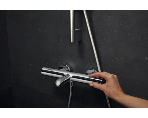 Utanpåliggande duschblandare med manuell manövrering mot mörk bakgrund.