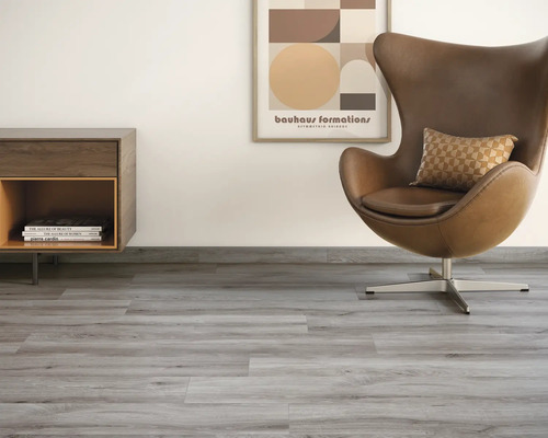 Vardagsrum med grått vinylgolv, fåtölj, byrå och väggmålning