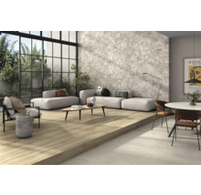 Ljust vardagsrum med klinkergolv i trälook, grå väggplattor och sittmöbler