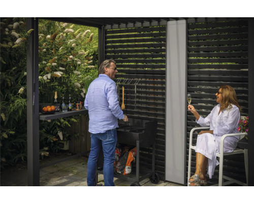 Trädgårdsfestscen med grill under ett terrasstak med lamellvägg