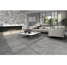 Vardagsrum med stengolv, öppen spis och grå soffa