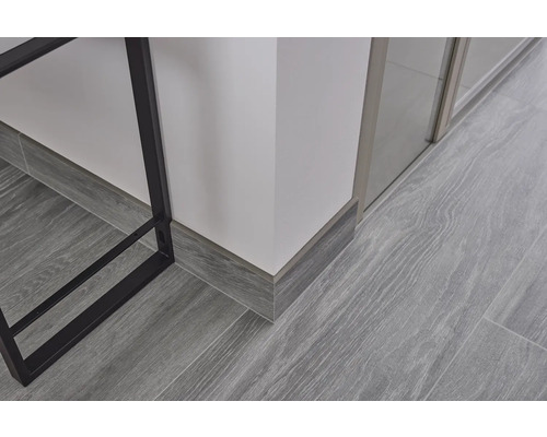 Detaljbild av laminatgolv med grått träutseende och golvlister