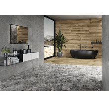 Modernt badrum med gråa plattor, tvättställ, spegel och fristående badkar.