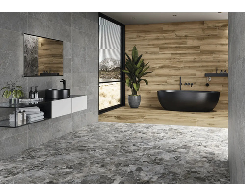 Modernt badrum med gråa plattor, tvättställ, spegel och fristående badkar.