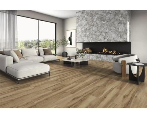 Vardagsrum med soffa, fåtölj, öppen spis och träimitation klinker för en ljus och rymlig atmosfär.