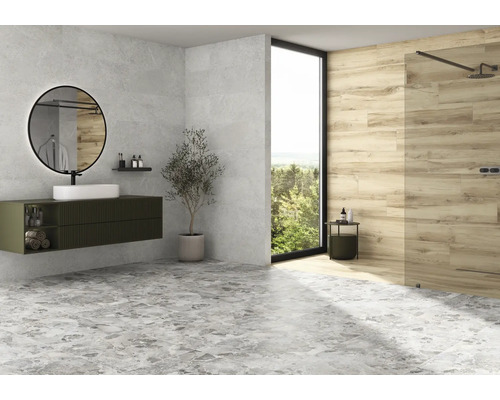 Modernt badrum med handfat, spegel, dusch och grått golvkakel.