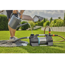 Person fyller en Gardena hydroforpump med vatten från en vattenkanna i trädgården.