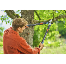 Man klipper trädgrenar med en växelgrensåg från Gardena.