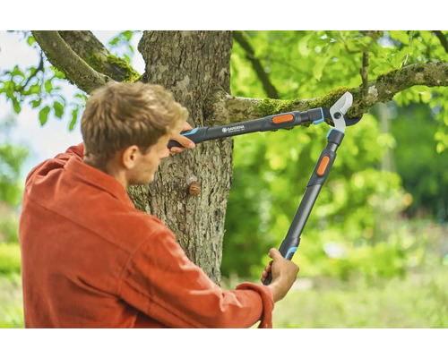 Man klipper trädgrenar med en växelgrensåg från Gardena.