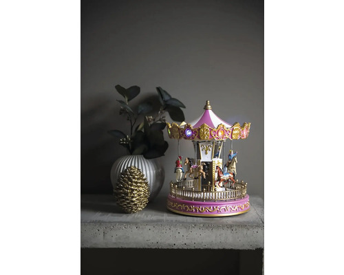 Dekorativ karusell med belysning, vas och kotte på ett bord