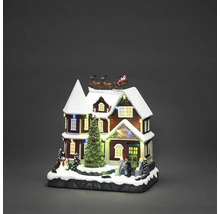 Belyst julhus med jultomten i släde och julgran som juldekoration