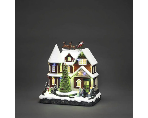 Belyst julhus med jultomten i släde och julgran som juldekoration