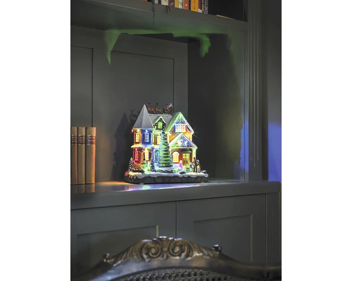 Dekorativt upplyst julhus på en hylla