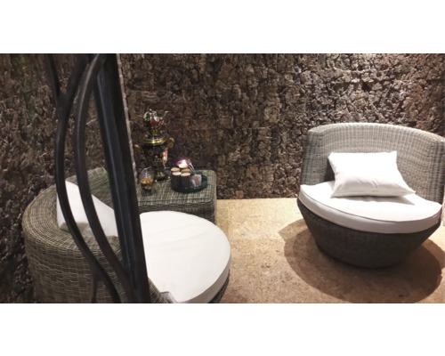 Vardagsrum med rottingfåtöljer, sidobord och dekorativa föremål framför en vägg