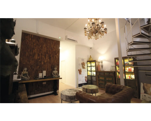 Interiörbild av ett ljust rum med möbler, dekorationer och en spiraltrappa