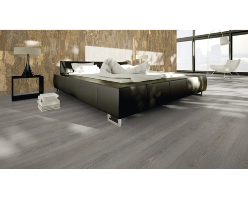 Sovrum med dubbelsäng, sänglampa och grått trägolv