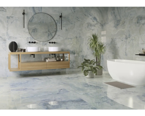 Ljust badrum med handfat, spegel, badkar och blå kakel