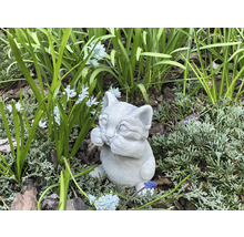 Dekorativ kattfigur av sten för trädgården, bland växter och blommor