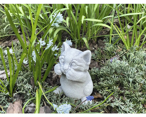 Dekorativ kattfigur av sten för trädgården, bland växter och blommor