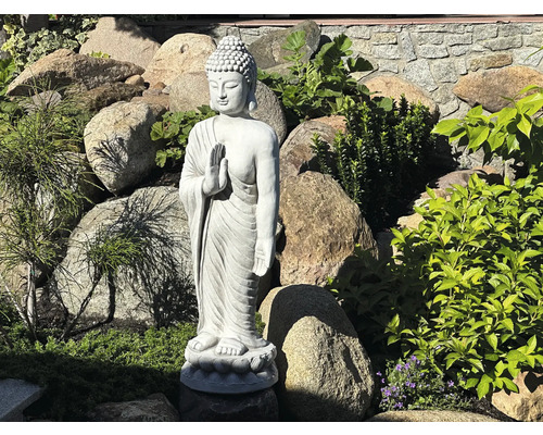 Buddha staty i trädgården mellan stenar och växter