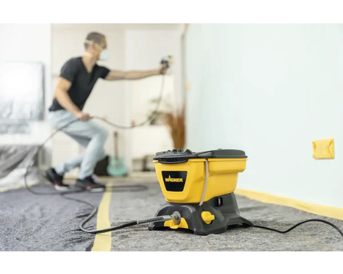 Färgspraysystem med en man som sprutar en vägg inomhus