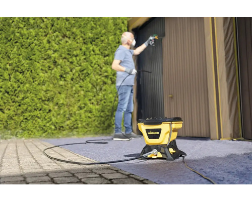 Man målar garageport med färgspraysystem från Wagner